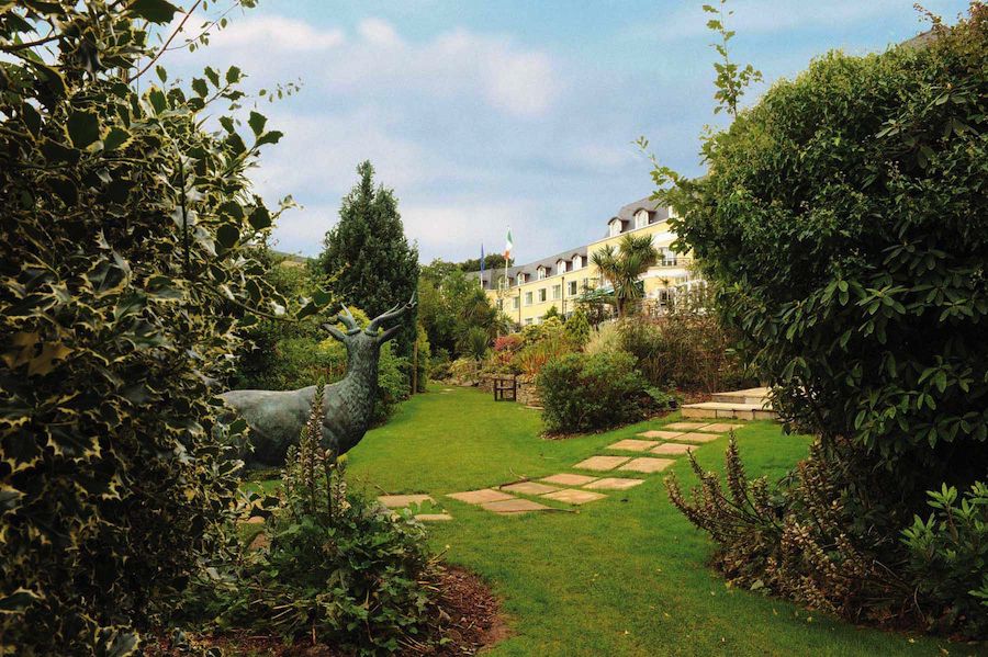 Grounds of Glenview Hotel, a deer statue surrounded by greenery faces the house