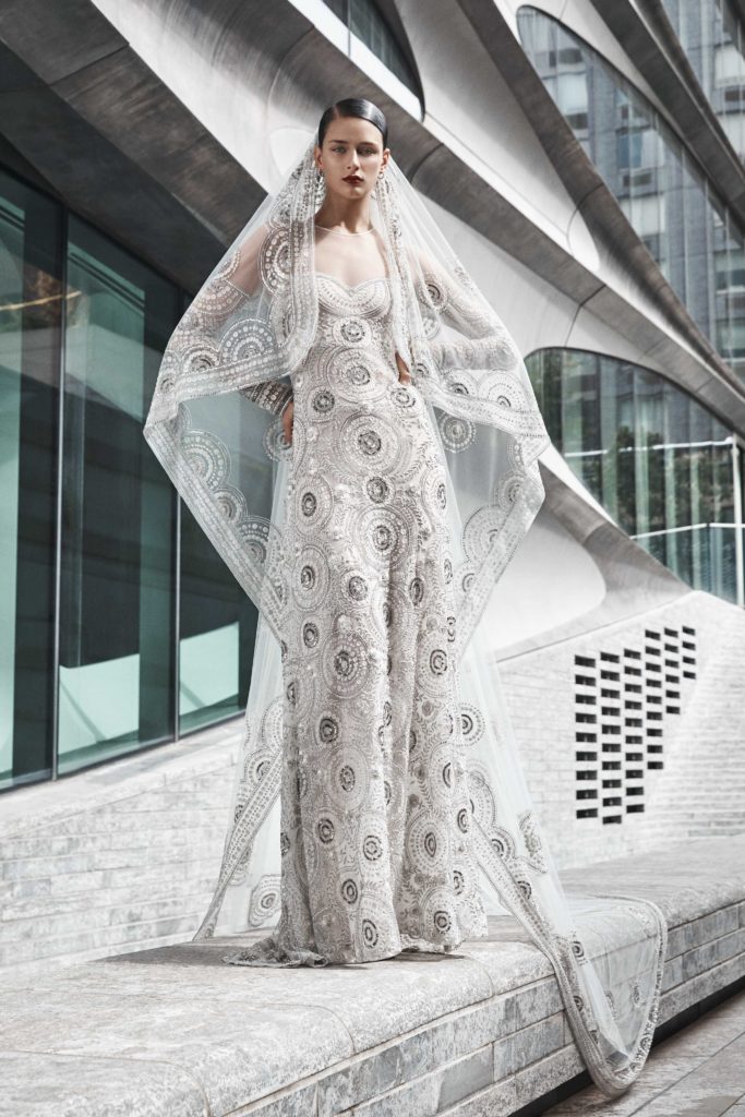 White, floor-length dress with silver circular embellishments and sweetheart neckline by Naeem Khan