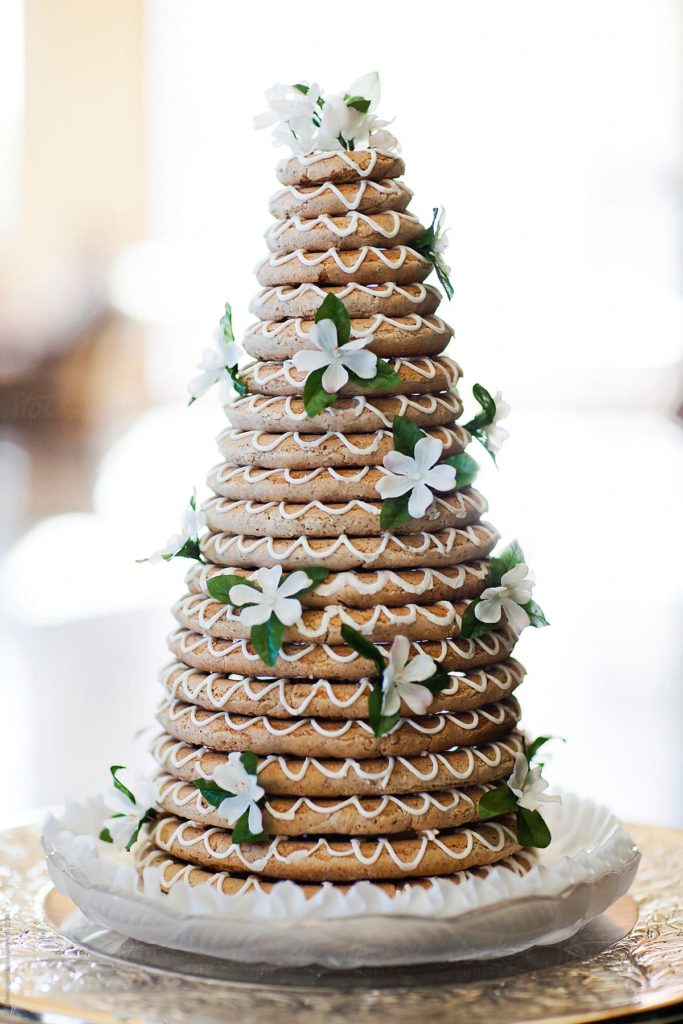 21 layers of Kransekake piled into a pyramid and decorated with white icing and white flowers 