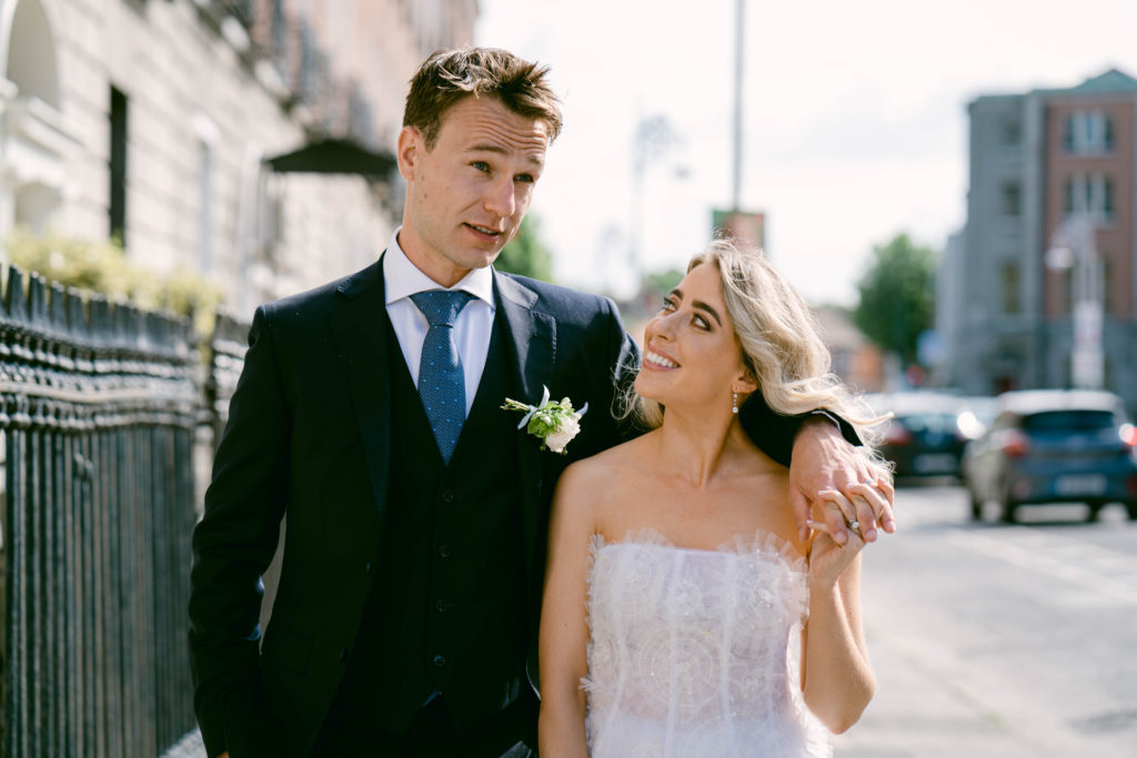 Bride and groom walking down a street in Dublin, Ireland; arm in arm