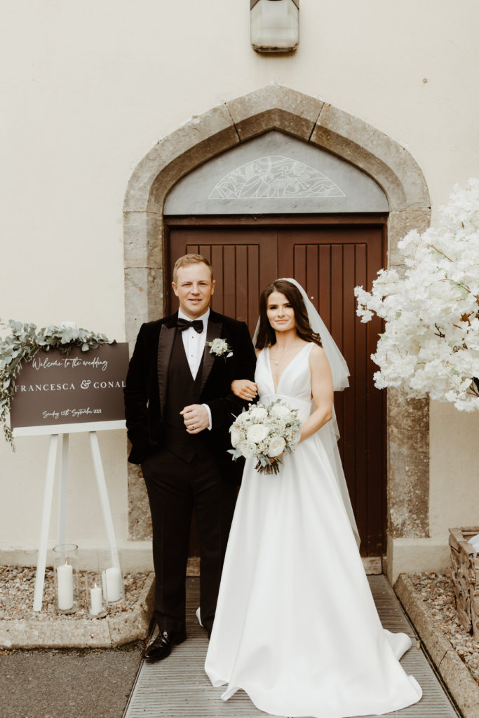 Irish bride and groom standing arm in arm outside a cathedral