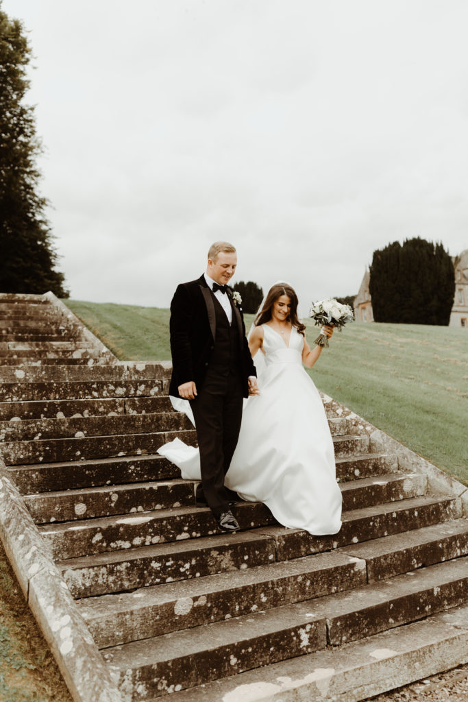 Irish bride and groom walking together down an old stone staircase on the grounds of Castle Leslie in Ireland