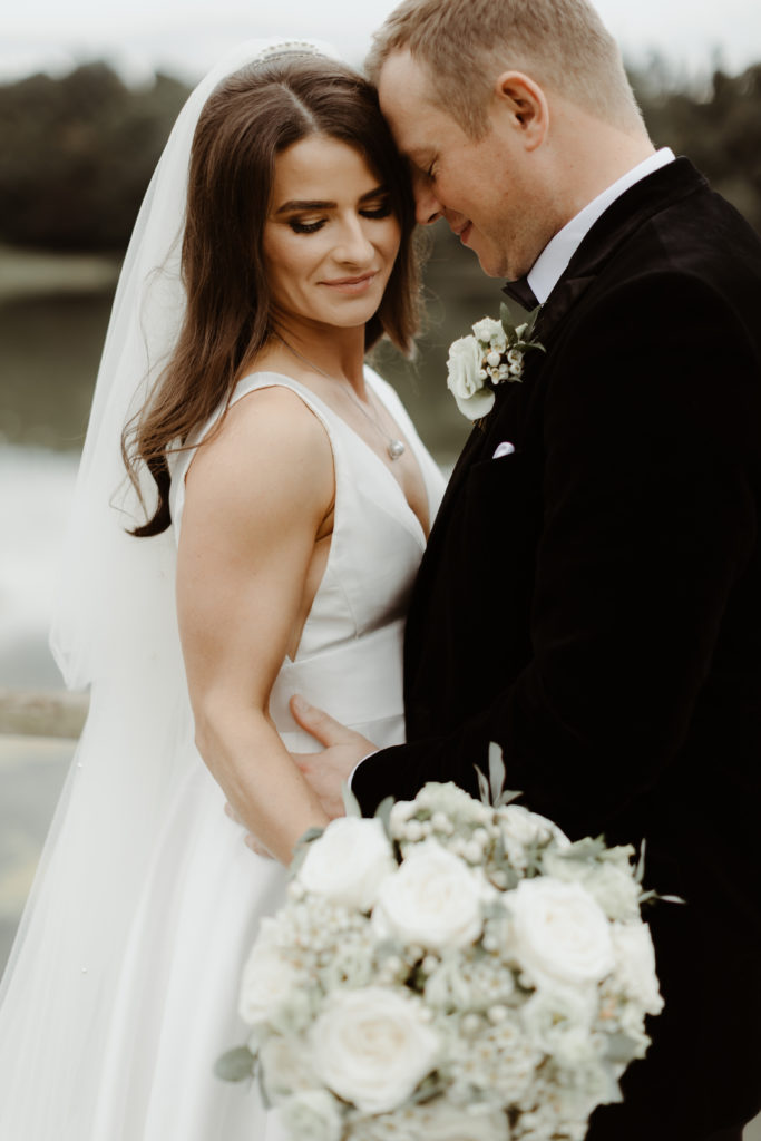 Irish bride and groom embracing in front of the lake on the grounds of Castle Leslie in Ireland