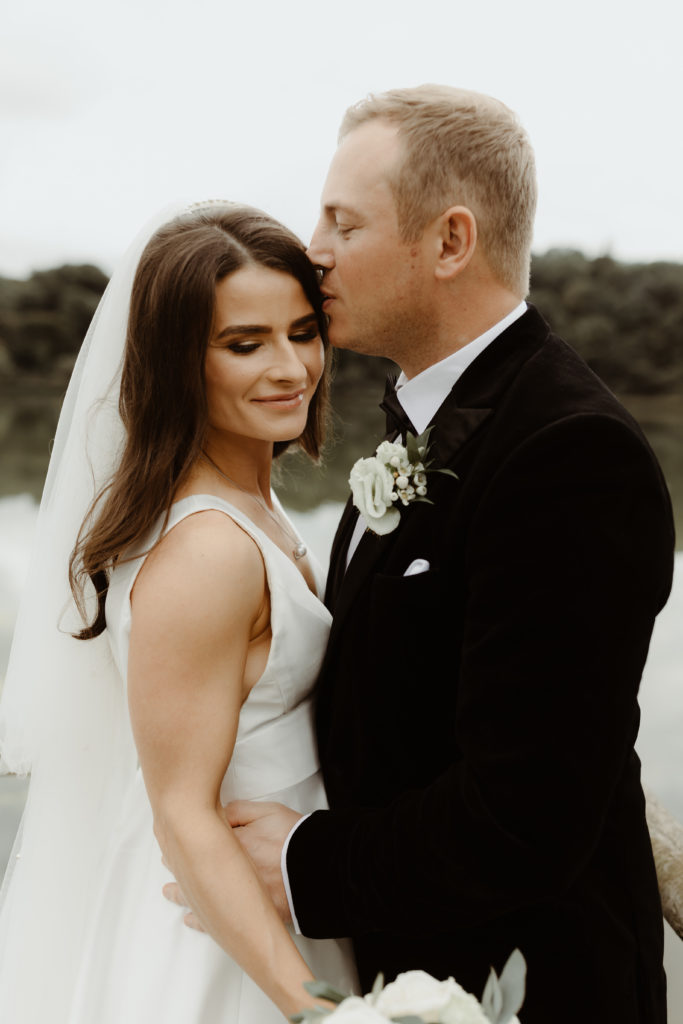 Irish bride and groom kissing in front of the lake on the grounds of Castle Leslie in Ireland