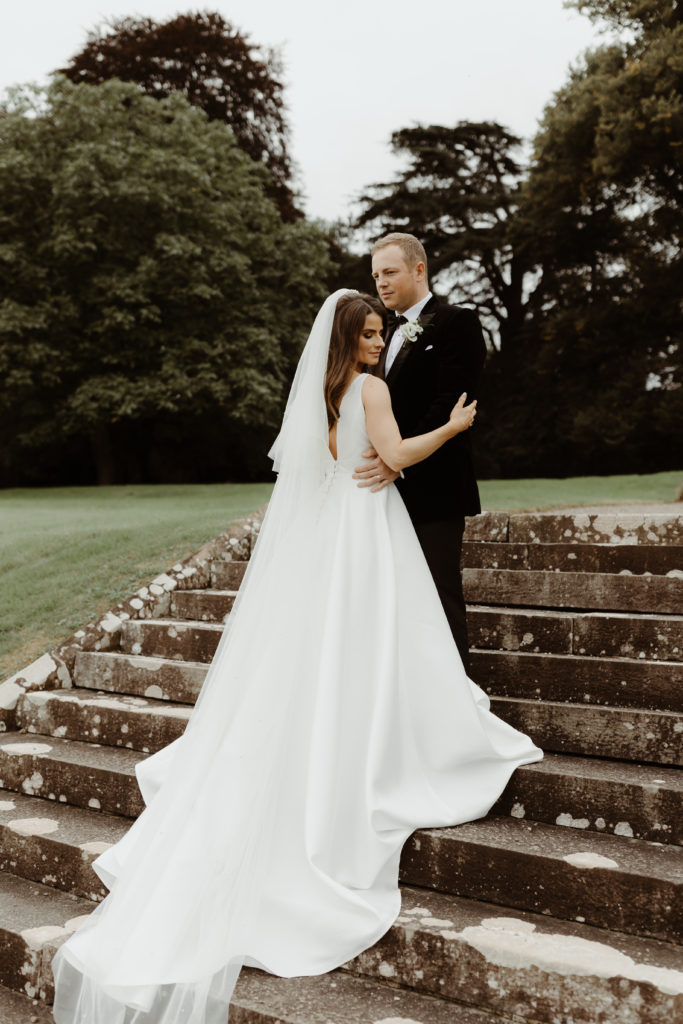 Irish bride and groom embracing on an old stone staircase on the grounds of Castle Leslie in Ireland